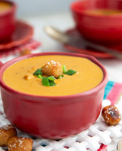 Beer Cheese Soup in a maroon colored ceramic bowl with handle