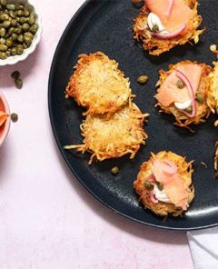Classic Latkes on a black plate topped with cream cheese and lox