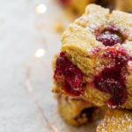 Closeup of Cranberry Orange Cornbread cut into a square with powdered sugar sprinkled on top
