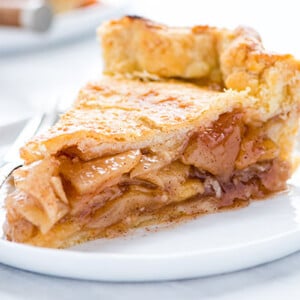 Closeup of a slice of Gluten-Free Apple Pie on a white plate with a silver fork on a white background
