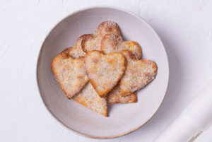 Overhead view of Heart-Shaped Sugar Cookies in a white shallow bowl on a white background