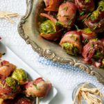 Overhead view of Maple Dijon Glazed Bacon-Wrapped Brussels Sprouts on a vintage platter on a lace tablecloth
