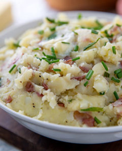 Mashed Red Potatoes in a white bowl topped with fresh chives