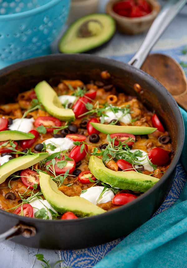 One Pot Enchilada Pasta in a skillet topped with sliced avocados