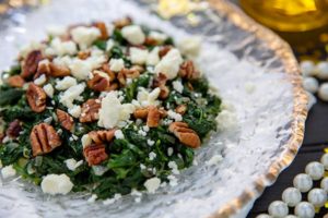 Closeup of Sauteed Spinach with Feta and Walnuts on a clear glass plate lines with gold