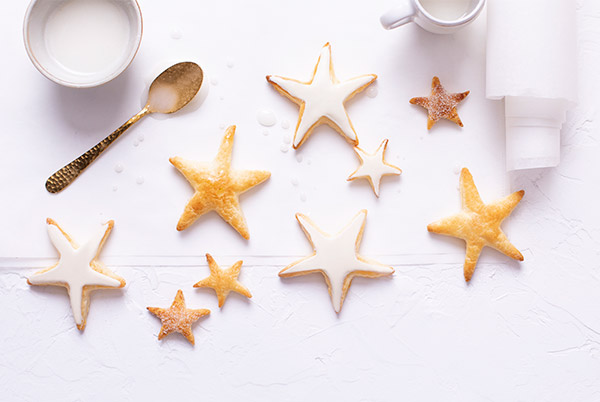 Vanilla Star Cookies on a white background with some cookies frosted and others left plain