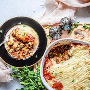 Vegan Shepherds Pie on a black and gold plate next to a white casserole dish