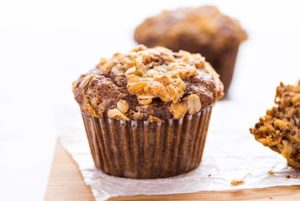 Closeup of Banana Oat Muffins on a piece of parchment paper on a light wood board with a white background