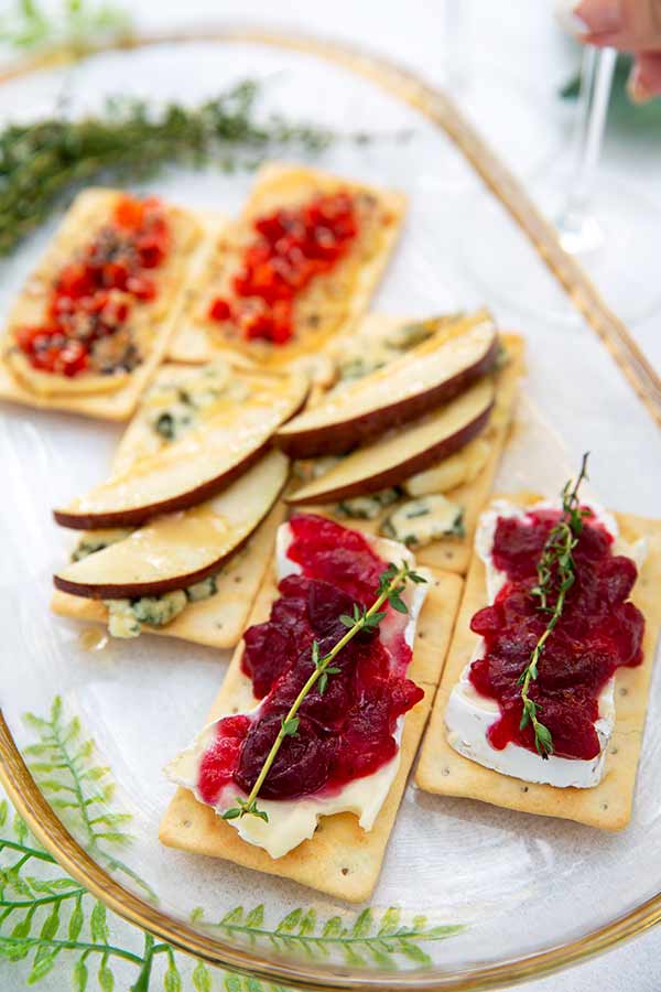Gluten-free crackers topped with three different combinations on a glass oval platter with gold rim
