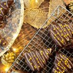 Flourless Christmas Tree Brownies on a wire rack and gold plate with Christmas lights and gold decorations around it