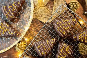 Flourless Christmas Tree Brownies on a wire rack and gold plate with Christmas lights and gold decorations around it