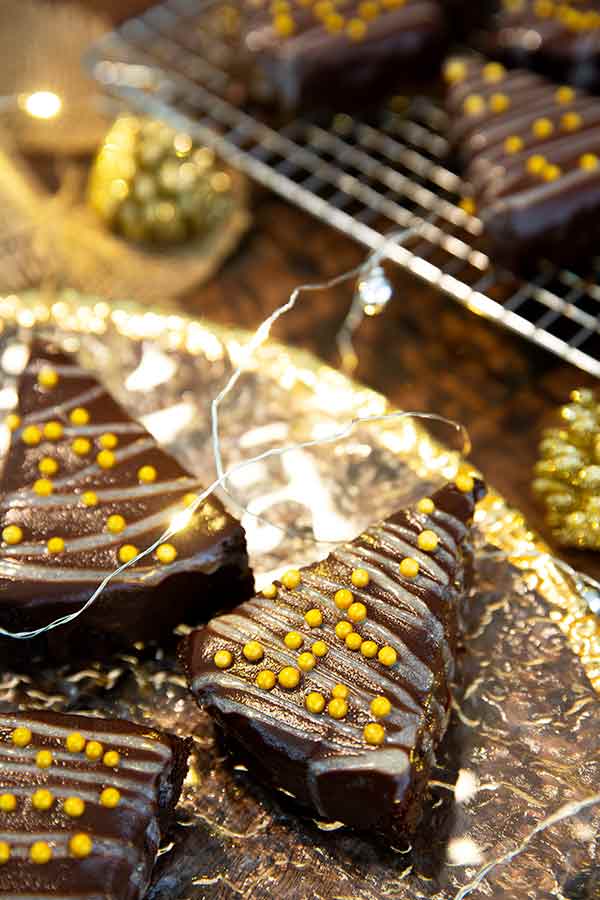 Flourless Christmas Tree Brownies on a gold plate with Christmas lights and gold pine cones around the plate