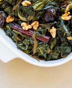 Closeup of Moroccan Style Winter Greens with walnuts and cinnamon sticks in a white casserole dish
