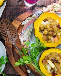 Overhead view of Stuffed Acorn Squash halves on white serving trays on a wooden background with fall napkins