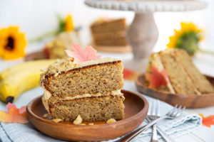 Slice of Sunbutter and Banana Cake with edible fall leaves on a brown wooden plate