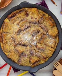Sunbutter and Jelly Bread Pudding in a cast iron skillet with colored pencils and wooden utensils around it