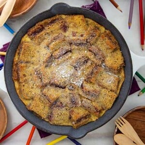 Sunbutter and Jelly Bread Pudding in a cast iron skillet with colored pencils and wooden utensils around it