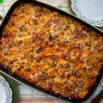 Overhead view of Sweet and Savory Bread Pudding in a casserole dish with white decorative plates on the side