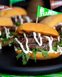Tenderloin Sliders on a black serving plate with football themed decorations in the background