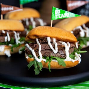 Tenderloin Sliders on a black serving plate with football themed decorations in the background