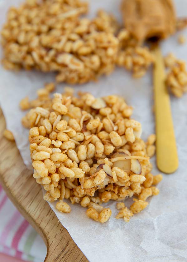 Closeup of Toasted Coconut Rice Crispy Bar on parchment paper on a light wood cutting board