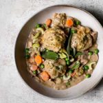 Vegan Chicken and Dumplings in a white bowl on a white marble background