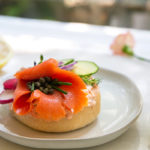 Bagels with Smoked Salmon Schmear topped with smoked salmon and capers on a white plate