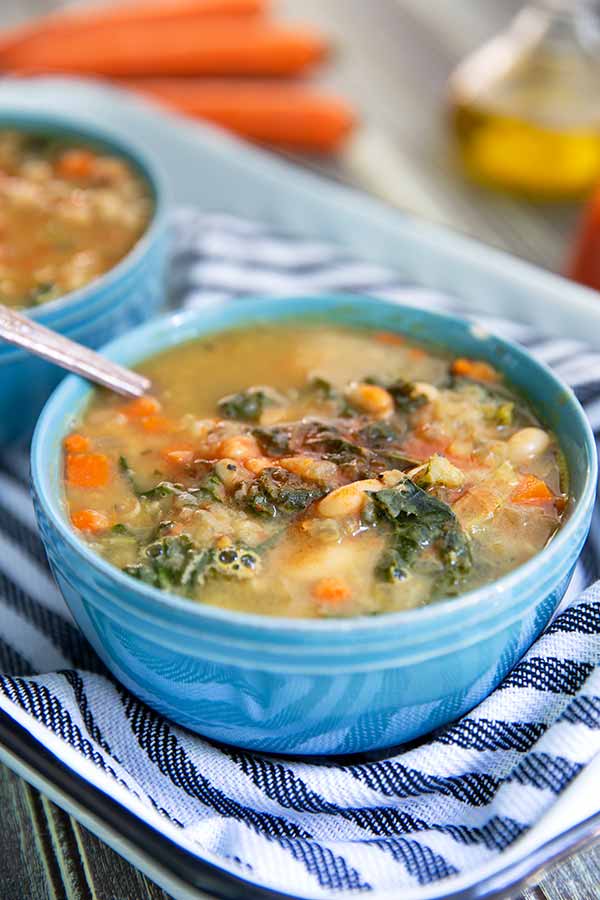 Creamy White Bean & Kale Soup in a baby blue bowl on a navy and white striped towel