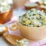 Easy Stovetop Spinach and Artichoke Dip in a white ramekin on a light pink and white checkered napkin