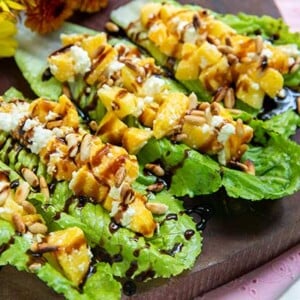 Endive Bites with Mango and Feta on a dark wooden board with yellow flowers in the background