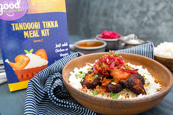 Good Its Gluten Free Tandoori Tikka Meal Kit on a gray background with a bowl of Chicken Tandoori Tikka in front of it