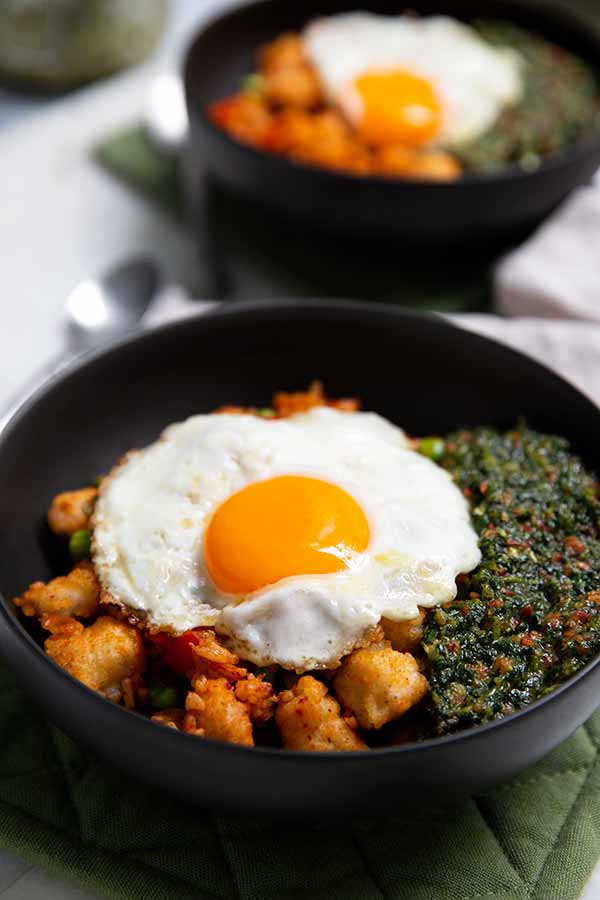 Korean Fried Rice with Cilantro Sauce topped with a fried egg in a black bowl