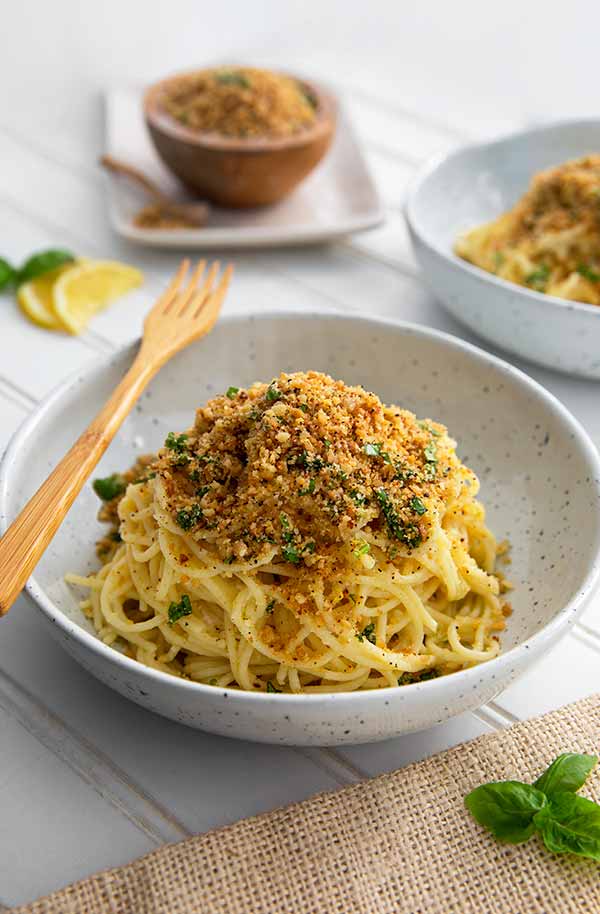 Lemon Pasta topped with breadcrumbs in a white bowl with wooden fork