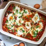 Make-Ahead Shakshuka in a white rectangle baking dish on a white background with gluten free pita bread