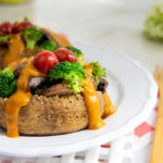 Plant-Based Baked Potato on a white plate with broccoli and tomato on top