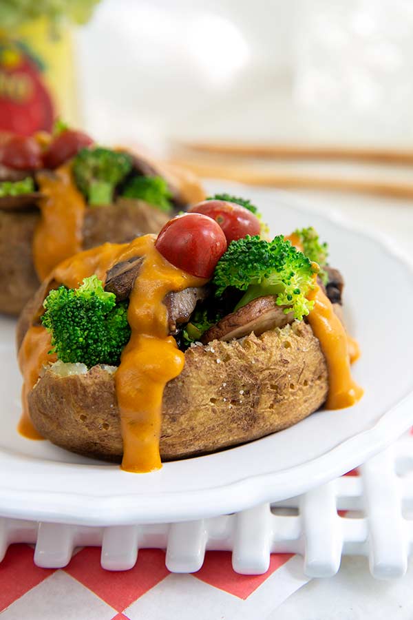 Plant-Based Baked Potatoes topped with broccoli and tomatoes on a white plate