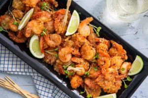 Overhead view of Salt and Pepper Shrimp on a black rectangular platter with lime wedges