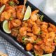 Overhead view of Salt and Pepper Shrimp on a black rectangular platter with lime wedges