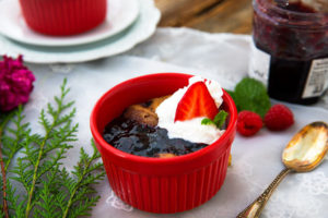 Sunbutter and Jelly Mug Cakes in red ramekins on a white lace tablecloth with raspberries and jam in the background