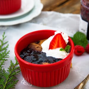 Sunbutter and Jelly Mug Cakes in red ramekins on a white lace tablecloth with raspberries and jam in the background