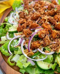 Tandoori Tikka Chicken Salad on a wooden serving plate with yellow napkin underneath