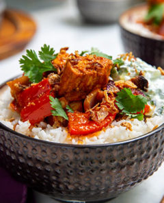 Tandoori Tikka Fish with Quick Raita over white rice in a bronze bowl with a dark purple napkin underneath and wooden chopsticks on the side