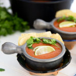 Tomato Tortilla Soup in a silver bowl topped with cilantro and lime
