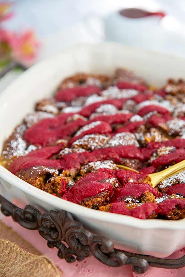 Closeup of Triple Berry Bread Pudding in a white casserole dish on a pink placesetting