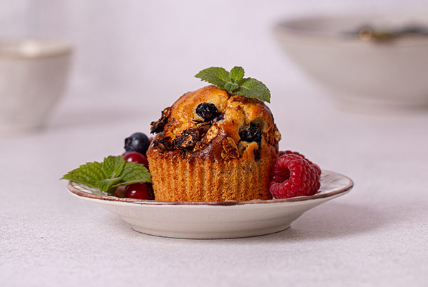 Very Berry Muffins garnished with fresh berries and mint leaves on a white plate with white background