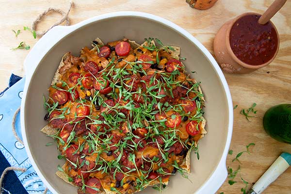 Overhead view of Plant-Based Tortilla & Jackfruit BBQ Casserole in a white bowl on light wood background