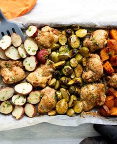 Overhead view of Chicken and Veggies Sheet Pan Dinner with a spatula and orange napkin