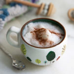 Kiddie Moon Milk in a white mug with childlike leaf drawings on the mug and cinnamon on top
