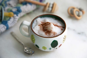 Kiddie Moon Milk in a white mug with childlike leaf drawings on the mug and cinnamon on top