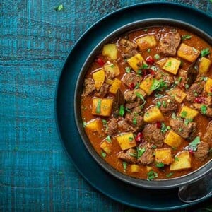 Lamb Vindaloo in a dark blue bowl on a dark teal background